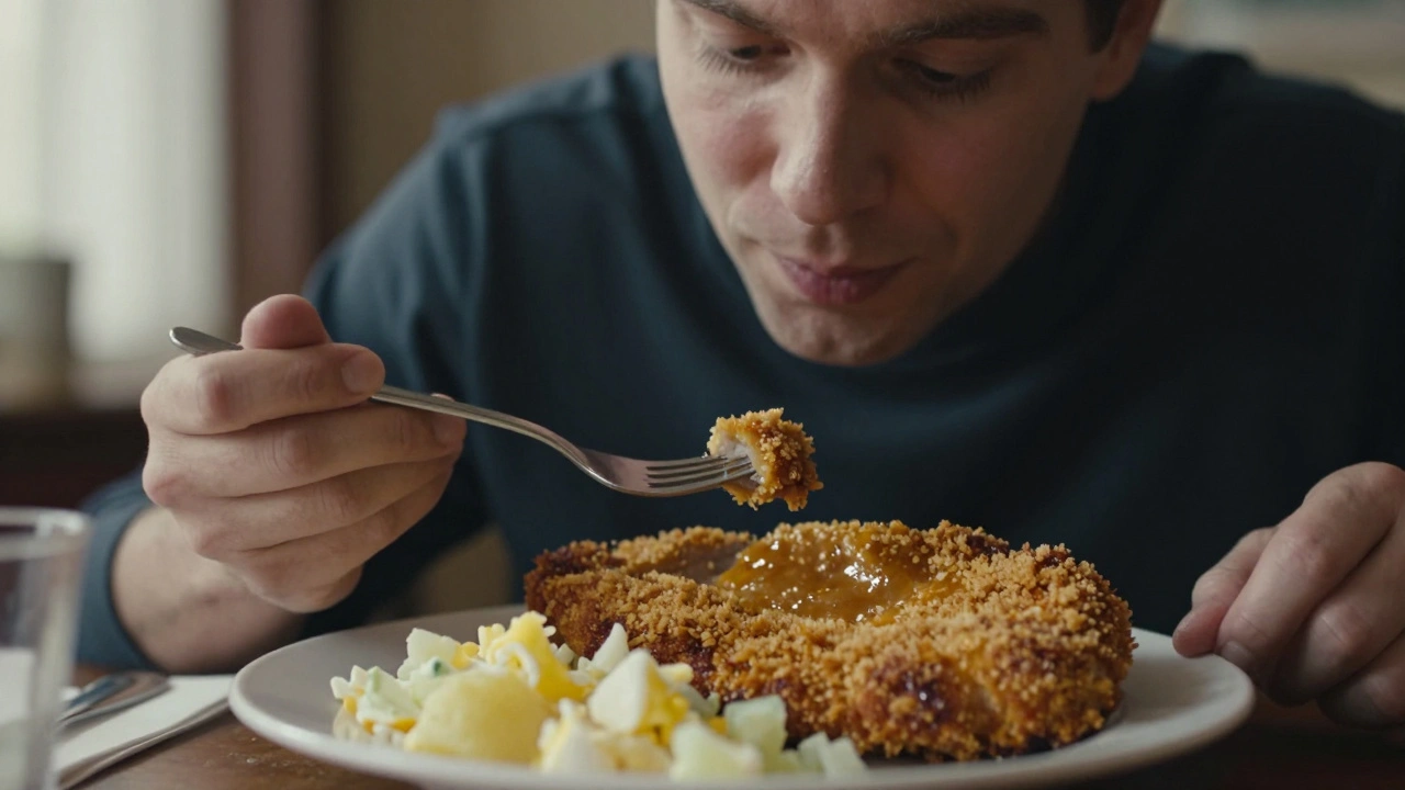 Klasický vepřový řízek s bramborovým salátem na talíři, ruka drží vidličku.